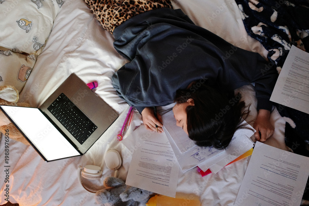 © Danil Nevsky/Stocksy - Exhausted student sleeping on study materials in bed