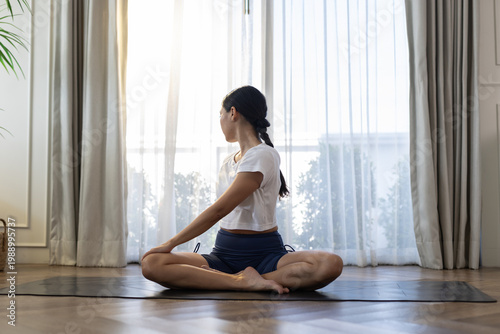 Photos woman practicing seated spinal twist yoga pose indoors near window