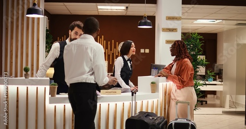 Obraz na plátně Friendly smiling concierge personnel assisting tourists with room registration