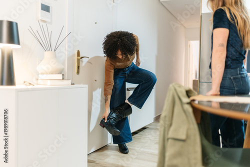Friend arriving home taking off boots