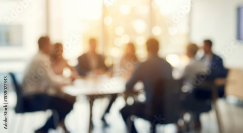 A blurred image of a business meeting with multiple professionals engaged in discussion around a conference table, creating a collaborative atmosphere.