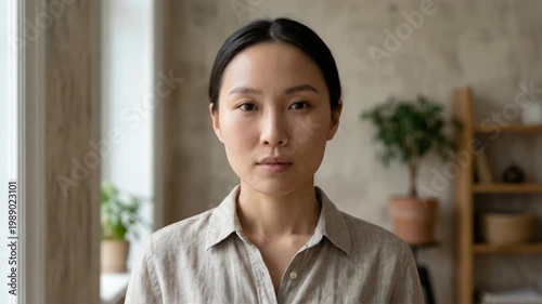 Calm Person Standing In Soft Natural Light. Gentle Window Light, Upright Body Language, And Quiet Portrait Framing Define The Scene. Two People Are Visible In Frame
