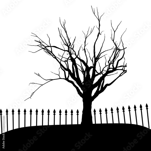Spooky silhouette of a gnarled, bare tree behind an old picket fence on a desolate hill