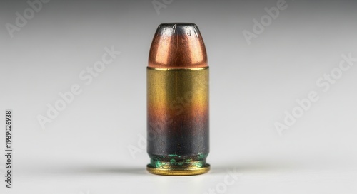 Individual pistol cartridge with striking metallic discoloration against a neutral backdrop