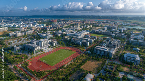 Aerial view of university campus with green lawn and red track geometric patterns. Glass buildings under sunlight with cinematic lighting. Blue sky copy space. 8K HDR render for education background.