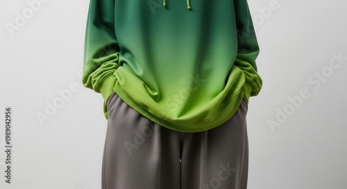 Stylish person showcasing modern green gradient hoodie and comfortable grey pants in a minimalist