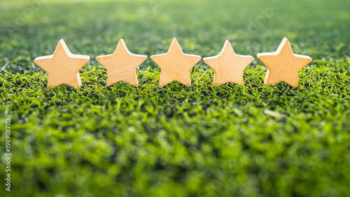 Fotografía Five wooden stars on green grass background for rating and ranking concept