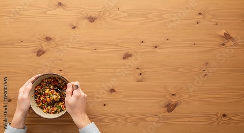 Person eating healthy quinoa grain salad on wooden table with copy space