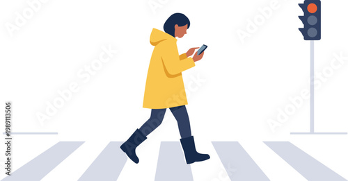 Person walks across a crosswalk while looking at phone under traffic light