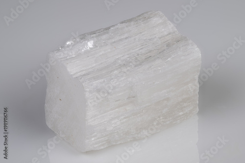 Studio shot highlighting translucent selenite with fibrous texture. Detailed photograph showcasing pearly translucent selenite on reflective background with fine striations