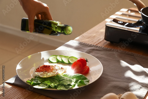 Hand pouring olive oil over...