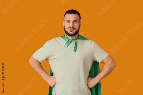 Foto Young man with superhero cape on orange background