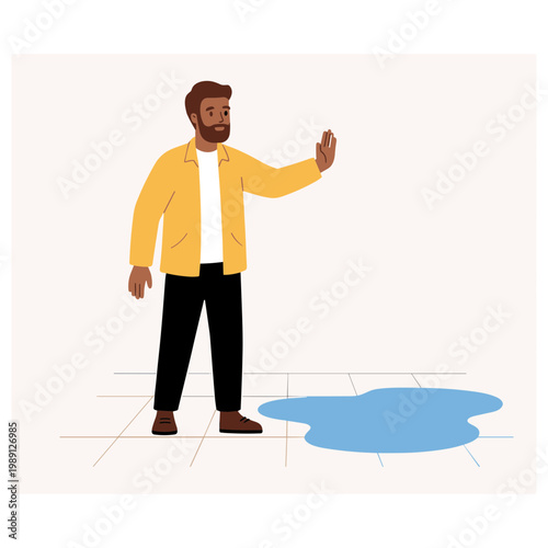 Man in yellow jacket gesturing towards a large blue water puddle on the floor indoors