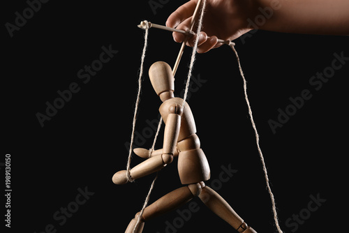 Foto Hand of puppeteer manipulating marionette on black background