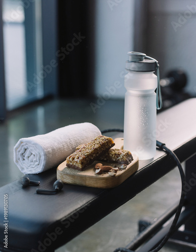 Healthy snacks and water bottle on a gym bench with a towel