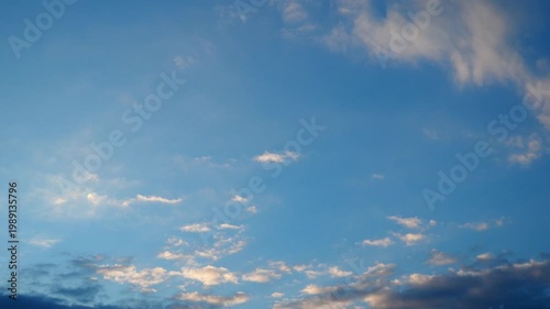 Clouds drift slowly across the sky as the sun sets. Birds fly high above the landscape. The colors change as evening approaches. The view shows a calm sky filled with nature.