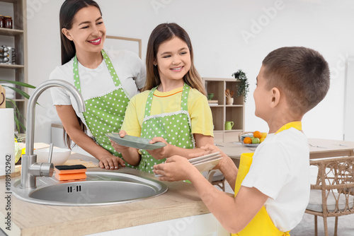 Quadro em tela Young mother with her children washing dishes in kitchen