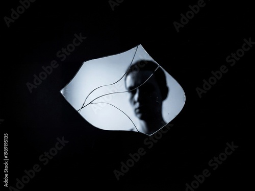 Broken Reflection: Silhouette in Shattered Mirror on Black Background
