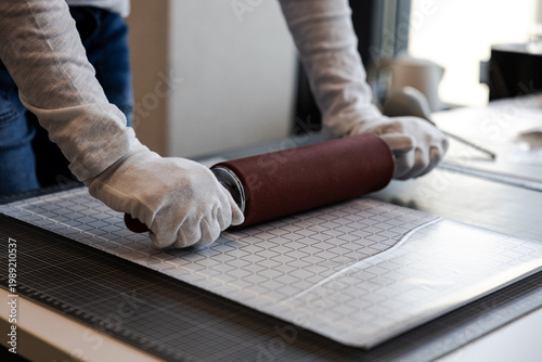 Fotografia Close-up of hands using a silicone rolling pin to smooth a printed image onto a surface