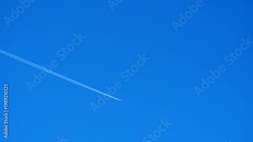 Planes fly across a clear blue sky, leaving long trails behind them. The activity takes place during day time with no clouds in view. A perfect day for flying shown here. Chemtrail conspiracy theory