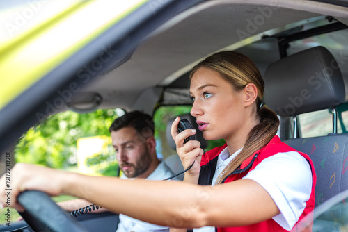 Photos Young female paramedic using a handheld radio transmitter while sitting in the driver seat of an ambulance