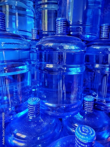 Stacked blue refillable water jugs in storage ready for delivery and distribution
