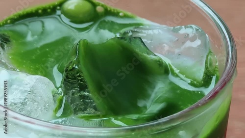 matcha tea being poured over ice in a glass.
