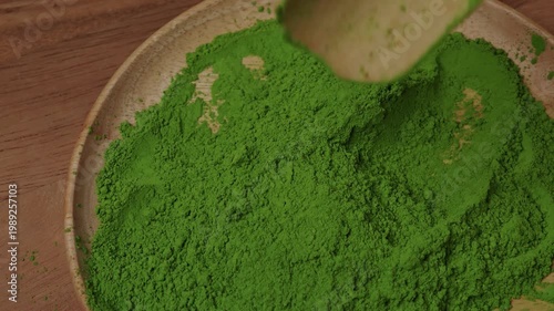 Matcha green tea powder mixing with a spoon