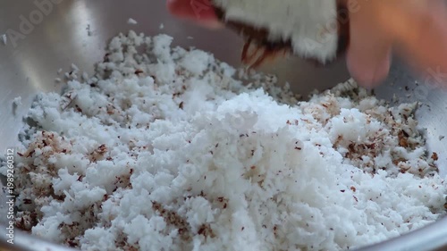 Traditional way, housewife sit on wooden coconut grater and grate coconut into container