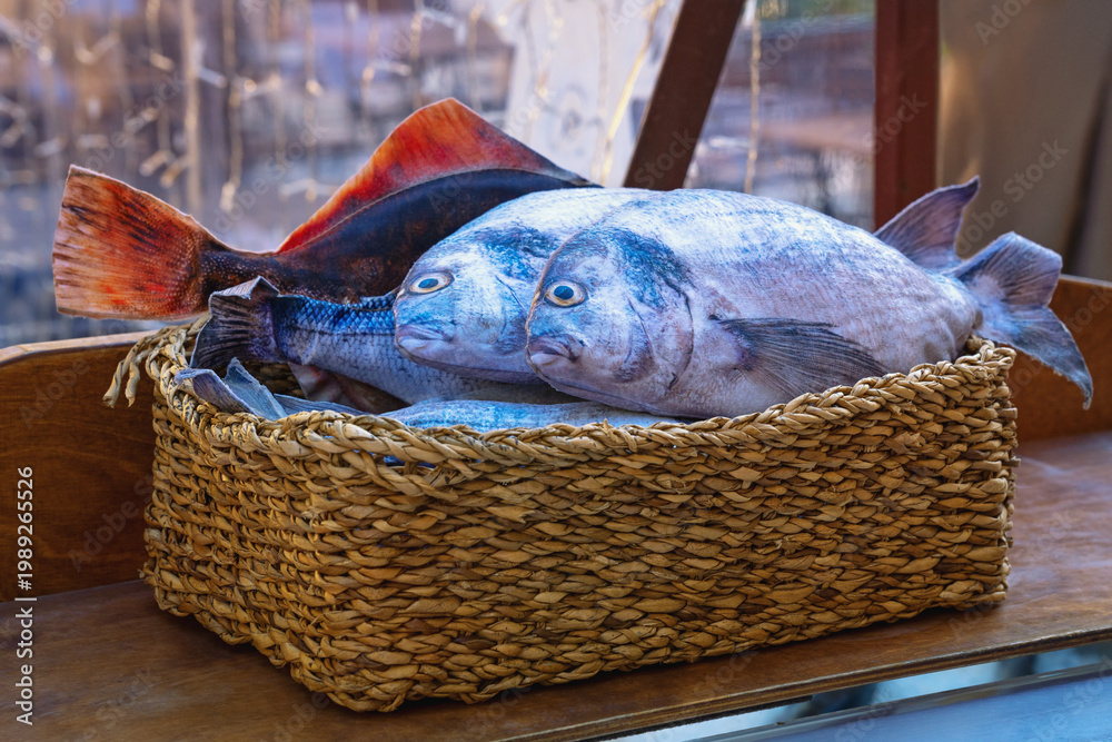 Obraz premium Fresh raw fishes ( sea bass, sea bream ) in basket on table