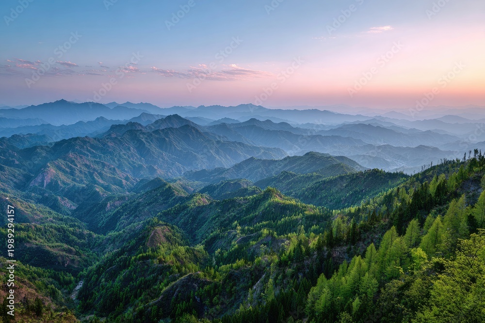 Fototapeta premium Lush, green mountain landscape receding into misty blue and pink twilight sky