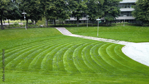 Freshly mown lawn in a park area with curved patterned lines on a sunny day