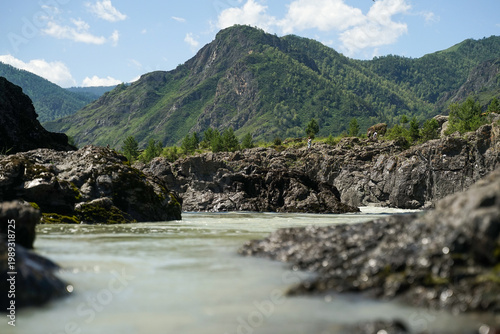 bright mountain peaks in summer, calm water flows along the river in the mountain environment