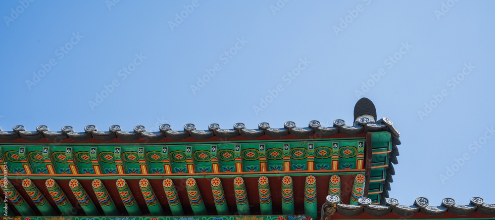 Naklejka premium Traditional South Korea architecture eaves with colorful dancheong patterns under a clear blue sky background
