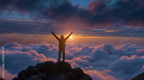Man with raised arms on mountain peak at sunset