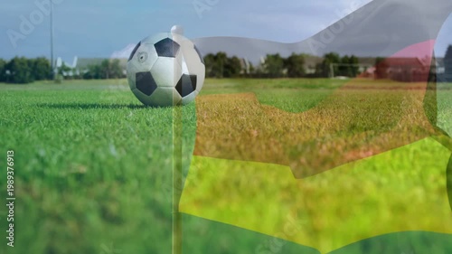 Soccer ball resting on grass while striped flag overlay appearing rippling revealing goal from wind