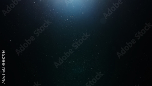 dust particles floating mid air over dark background with some lens flare
