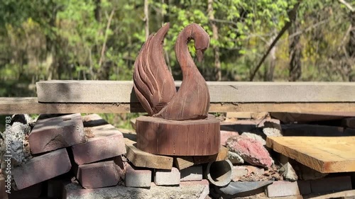 Wooden swan sculpture in garden setting, decorative art concept, handmade carving, outdoor design, natural materials, rustic aesthetic scene
