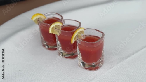 Three small glasses with red drinks and lemon slices, beverage and refreshment concept, party shots, summer drinks, minimal clean composition