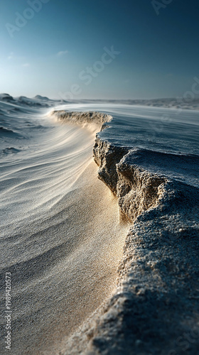 Frozen snow ridge in a remote winter landscape with dramatic sunlight, blue sky, and wind-shaped icy terrain.