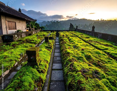 Green Moss Covered Stone Terraces In Balinese Temple Landscape At Sunrise With Misty Tropical Mountains Background