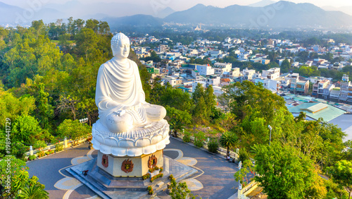 Fotografie A majestic view of the giant white Buddha statue at Long Son Pagoda, Nha Trang, Vietnam peacefully seated atop a hill overlooking the city