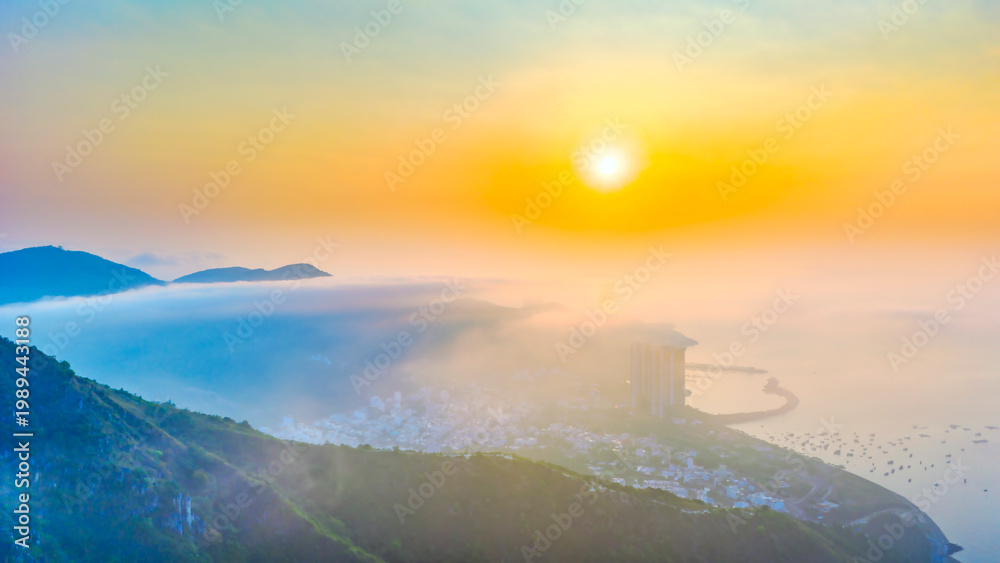 Fototapeta premium A breathtaking sunrise view over the mountains surrounding Nha Trang city, Vietnam. Where golden sunlight spreads across a sea of clouds.