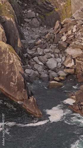 Dramatic ocean waves crash against rugged rock formations on a wild coastal shore.