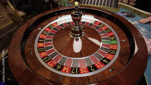 Hand spinning roulette wheel with ball in casino, close up