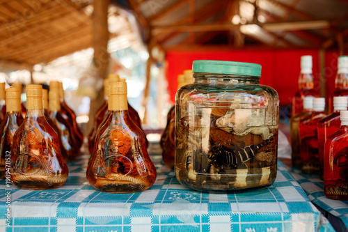 Canvas Print Bottles and a jar of traditional infused liquor with preserved snake and scorpion displayed at a market stall