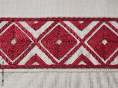 A detailed close-up of a traditional textile border featuring repeating geometric red patterns