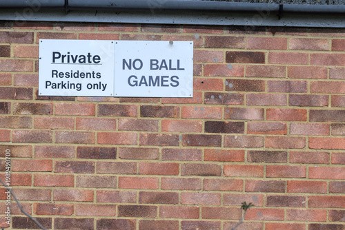 Private residents parking sign and no ball games notice on brick wall