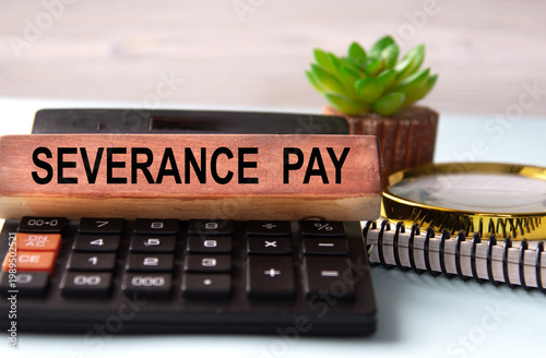 SEVERANCE PAY - words on a wooden block with a calculator in the background