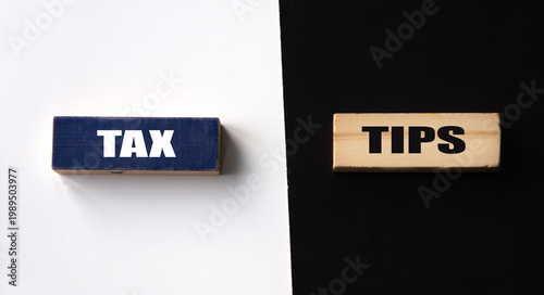 TAX and TIPS - words on wooden blocks on a black and white background